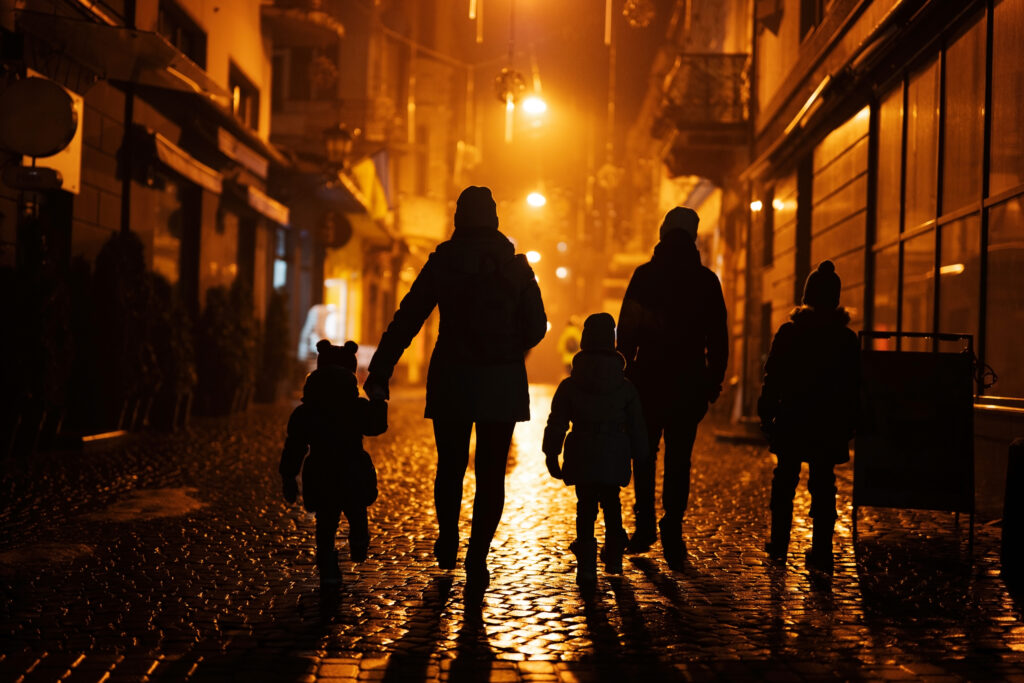 Family holds hands walking down the street at night