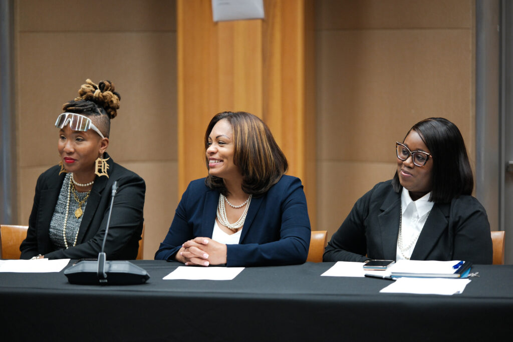 Three individuals sit at a meeting.